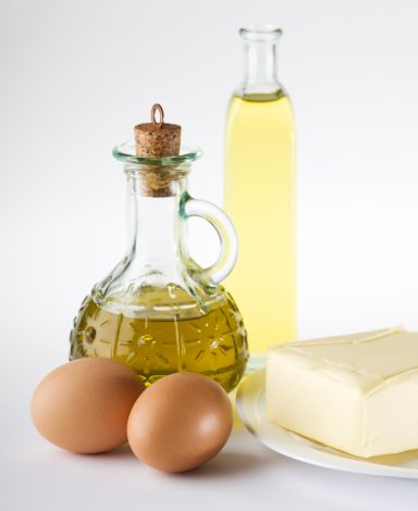 Huile d'olive, oeufs, beurre sur une assiette, fond clair.